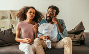 Couple in front of fan because AC is broken